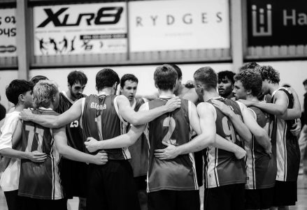 A team huddled together with arms around each other